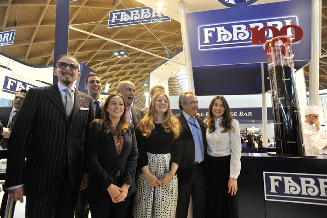 la famiglia Fabbri allo stand dell’omonima azienda posa di fianco alla colonna contenente le seimila amarene